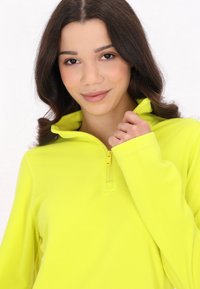 Lys gul fleece pullover med halvlukket krave. Har en blød tekstur og lange ærmer med fine sømdetaljer.