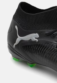 Black football boot with a textured upper, featuring a silver Puma logo and green studs. Knitted collar and lacing system for security.