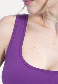 Lila linne med breda axelband och rundad halsringning. Slät, stretchig tyg med matt finish och minimala sömdetaljer.