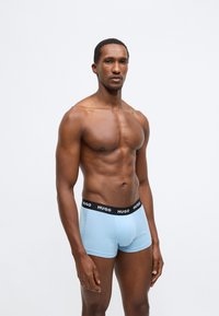 Boxer a vita bassa azzurri realizzati in cotone elasticizzato, con elastico nero in vita con il marchio "HUGO". Design liscio e aderente.