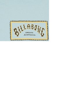 Hellblaues T-Shirt mit einem rechteckigen Grafik in Gelb und Schwarz, auf dem "BILLABONG" steht, sowie dem Text "SINCE 1973" und "AUSTRALIA".