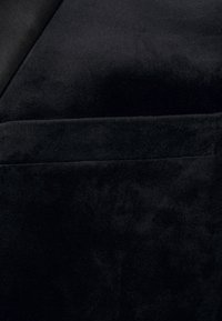 Černá plyšová tkanina s měkkým, texturovaným povrchem, která má hladký finiš a jemný lesk. Čistý, moderní design bez viditelných vzorů.