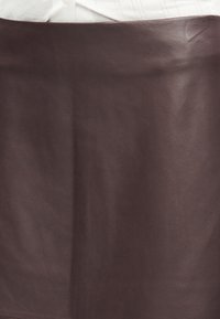 Jupe en cuir marron à texture lisse, présentant un design épuré et simple avec une silhouette droite.