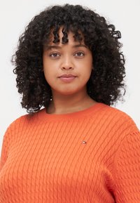Oranger gerippter Pullover mit Rundhalsausschnitt und kleinem Logodetail. Verfügt über einen strukturierten Stoff und einen lässigen Schnitt.