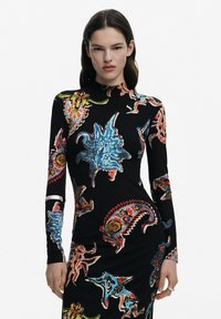 Langärmliges Kleid aus geripptem Stoff, schwarzer Grund mit mehrfarbigen Blumen- und abstrakten Mustern. Stehkragen, figurbetonte Silhouette und kontrastierende Manschetten.