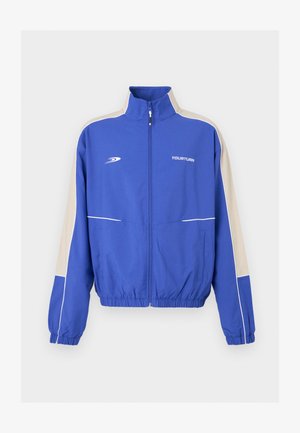 Veste de survêtement bleue zippée avec bandes latérales beiges, poignets et ourlet élastiques, et logo "YOURTURN" sur la poitrine.