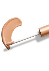 Produit de maquillage liquide avec un applicateur en forme de baguette douce et arrondie ; formule crémeuse de couleur tan étalée en ligne courbe.