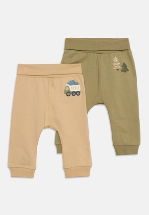 Deux pantalons pour bébé, l’un beige avec un motif de camion benne, l’autre vert olive avec deux dessins d’arbres, tous deux avec ceinture et poignets élastiques.