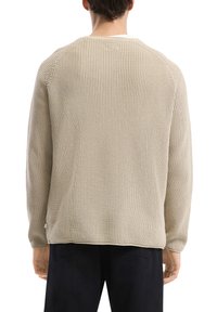 Beige gebreide trui met een losse, gestructureerde weef, met een ronde halslijn en lange mouwen, van achteren weergegeven.