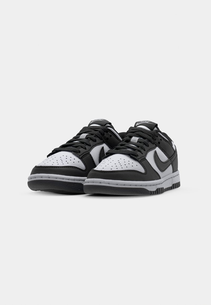 Sneaker atletici in bianco e nero con punta perforata, lacci piatti, collare imbottito e suola in gomma con accenti testurizzati.