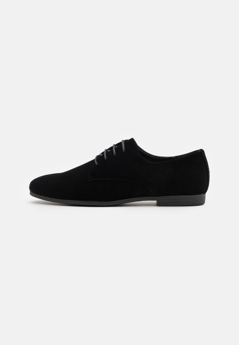 Czarne zamszowe buty wizytowe o gładkiej fakturze, smukłym profilu i szarych sznurówkach. Posiadają niską gumową podeszwę i minimalistyczny design.