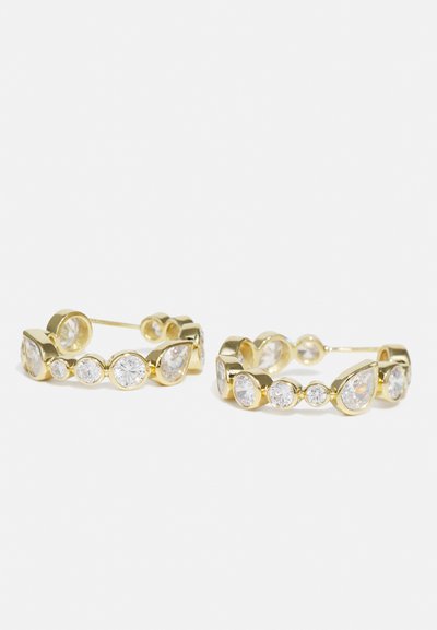 Aukso hoop auskarai su pakaitomis apvaliais ir lašo formos skaidriais rhinestone akmenimis. Lygi tekstūra su blizgiu užbaigimu, su saugia uždarymo sistema.