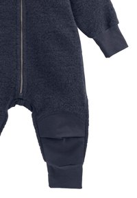 Navyblauwe jumpsuit met rits, gemaakt van zachte fleece met ribgebreide manchetten. Heeft contrasterende, bewerkte kniestukken en een relaxte pasvorm.