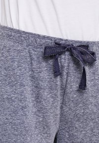 Gray lounge pants with a soft texture, elastic waistband, and a navy drawstring tie. The fabric has a heathered pattern.