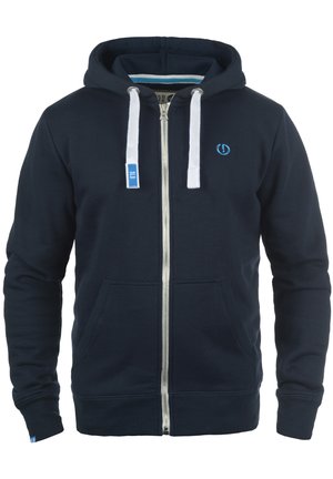 Marineblaue Zip-Up-Hoodie mit weißen Kordeln, seitlichen Taschen, gerippten Bündchen und blauem Logo auf der Brust, aus weichem Material gefertigt.