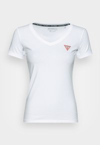 Camiseta blanca ajustada con cuello en V, de manga corta, que presenta un logotipo triangular rojo en el lado izquierdo del pecho y una cinta de cuello negra de la marca.
