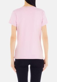 T-shirt rosa chiaro a maniche corte realizzato in cotone morbido, con un design aderente classico, un collo rotondo e una texture liscia.