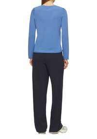 Niebieska koszula z długim rękawem i okrągłym dekoltem, zestawiona z ciemnogranatowymi spodniami. Koszula ma gładką fakturę i dopasowany krój.