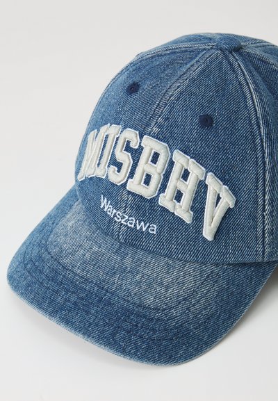 Boné de basebol em denim azul com texto branco bordado "MISBHV" e "W Warszawie." Apresenta uma coroa arredondada e aba levemente curvada.
