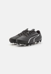 Scarpe da calcio nere con materiale sintetico liscio, presentano accenti bianchi, design con lacci e molteplici tacchetti neri e bianchi sulla suola.