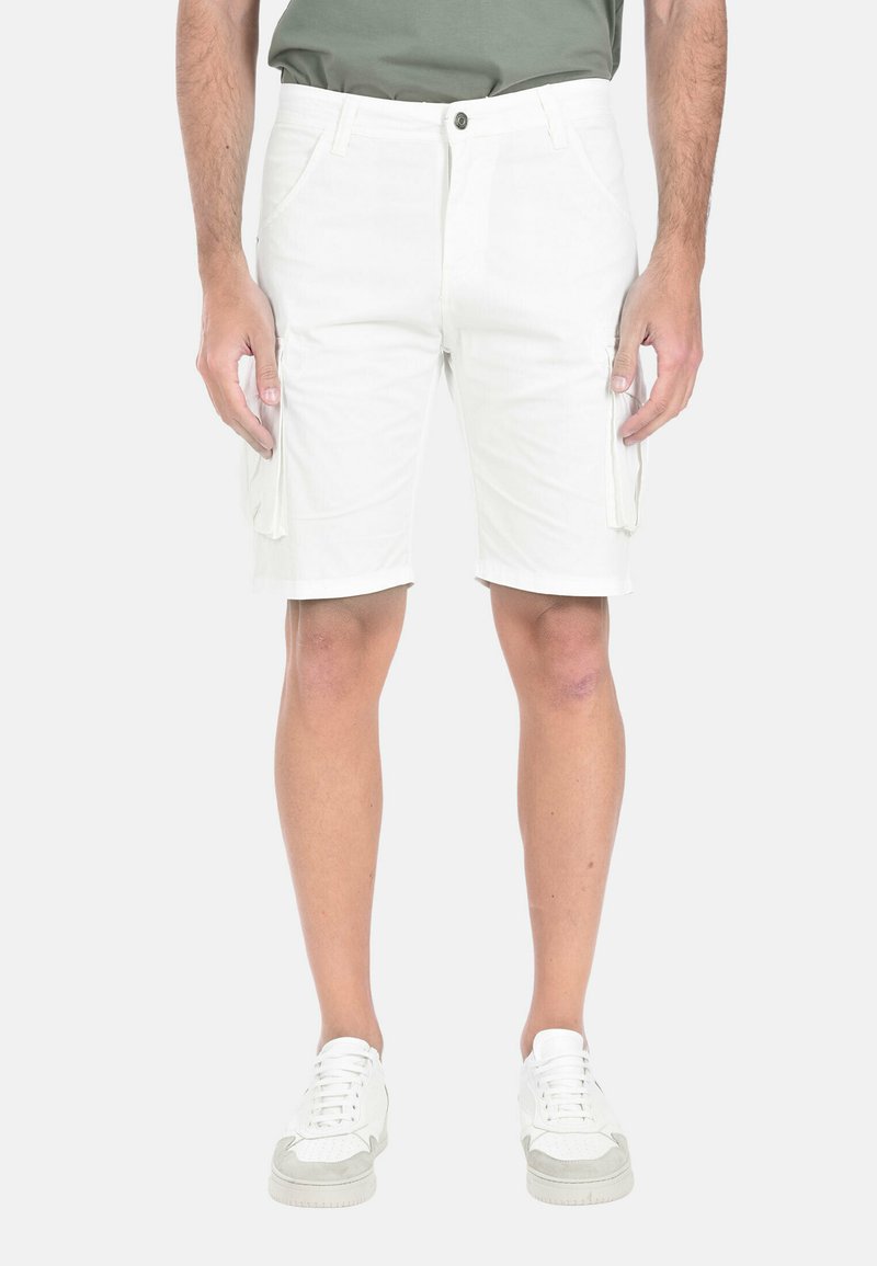 Pantaloni cargo bianchi con tasche laterali, un tessuto leggermente texturizzato e una vestibilità comoda, abbinati a scarpe da ginnastica bianche.