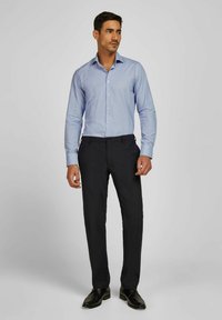 Lichtblauw geruit overhemd met lange mouwen, gestructureerde kraag en knopen, gecombineerd met donkere op maat gemaakte broek en zwarte schoenen.