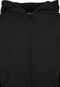 Sweat à capuche noir zippé avec poches frontales et fermeture éclair visible au milieu.