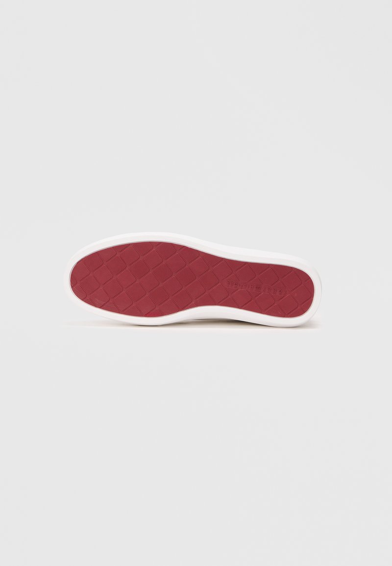Red rubber shoe sole with a textured diamond pattern, surrounded by a white perimeter. Designed for grip and durability.