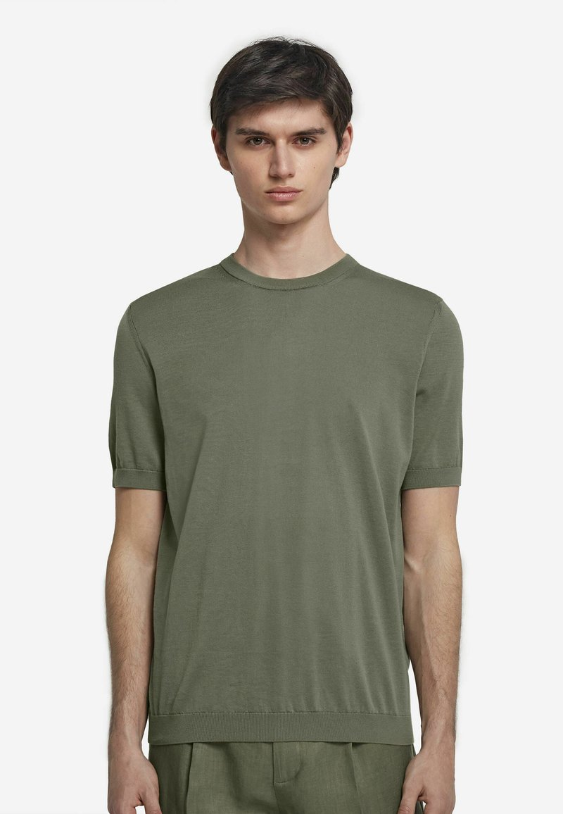 T-shirt med kort ärm och rund halsringning i olivgrön färg, tillverkad av mjukt tyg med en slät yta; har uppvikta ärmar och en något avslappnad passform.