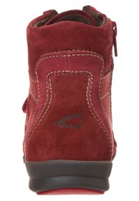 Bottine en daim rouge avec semelle en caoutchouc noir. Présente des accents de couture et une fermeture zippée à l'arrière pour un enfilage facile.