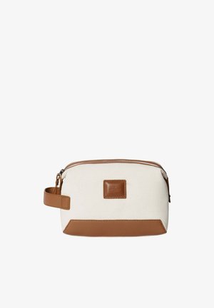 Bolsa de lona con cuerpo color crema, detalles en cuero marrón, cierre con cremallera y asa lateral para facilitar su transporte. Cuenta con un parche con el logo en el frente.