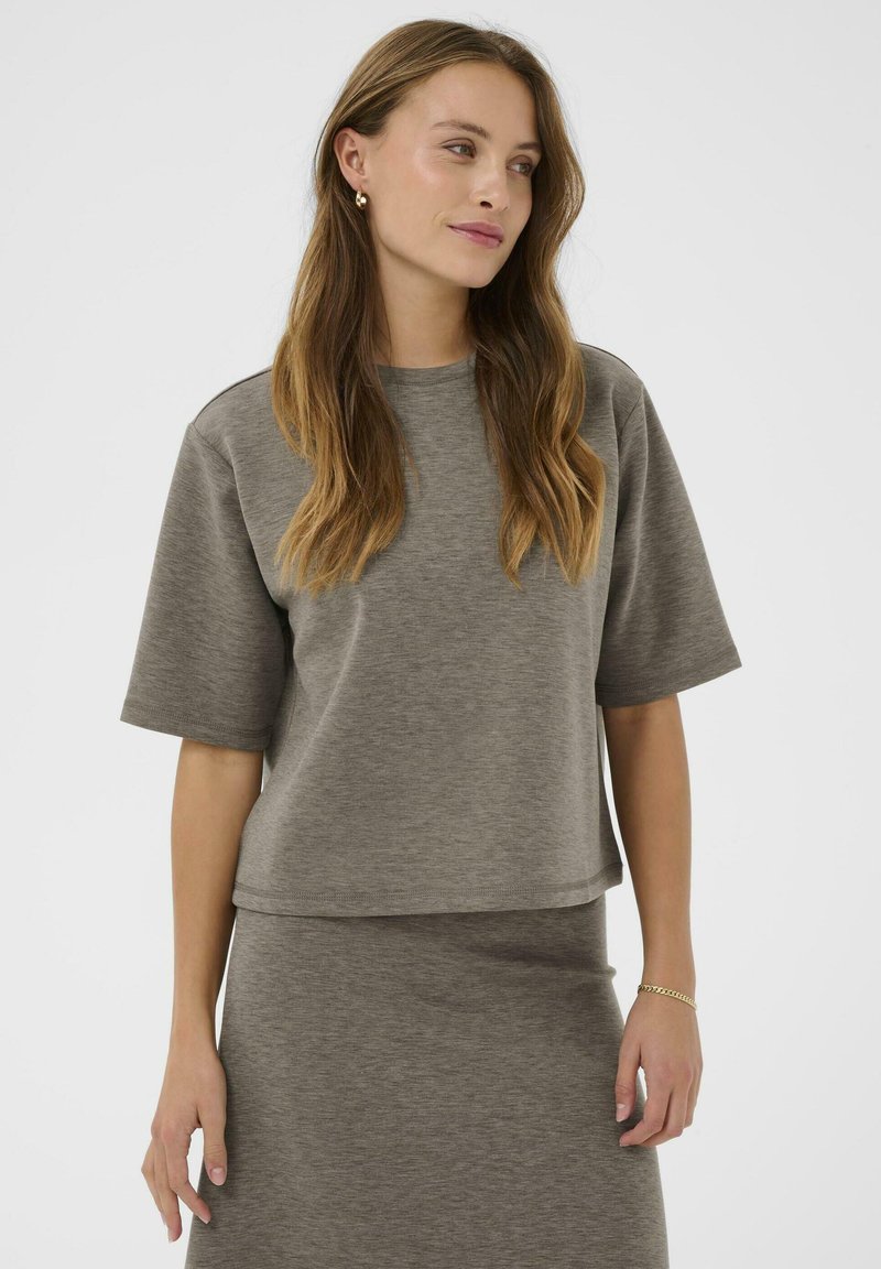 Harmaa puuvillasekoitteinen paita lyhyillä hihoilla ja rento istuvuus, jossa on pyöreä pääntie ja pehmeä tekstuuri. Yhdistetty vastaavaan harmaaseen hameeseen.