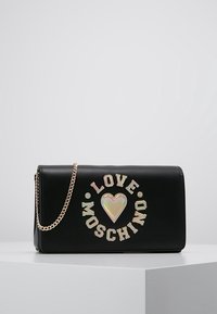 Svart läderhandväska med guldkedjesläp, med "LOVE MOSCHINO" logotyp och ett hjärtdesign i iriserande material på framsidan.