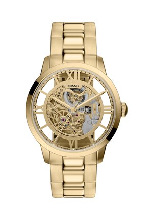 Goudkleurig skeletuurwerk met Romeinse cijfers, roestvrijstalen schakelarmband, zichtbare bewegingsdetails en gepolijste afwerking.