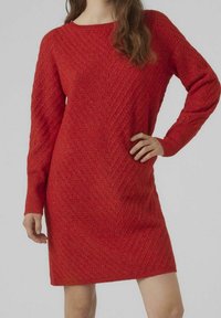 Robe en tricot rouge avec un motif en chevrons, manches longues et encolure ronde. Texture lisse et longueur au genou.