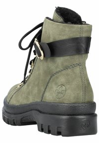 Botte chevillère en suede verte avec sangle en cuir noir, lacets, matériel en métal doré et semelle en caoutchouc texturée ; présente un détail de logo embossé sur le côté.