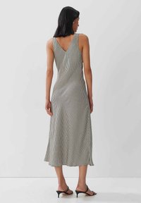 Schwarz-weiß kariertes Midi-Kleid mit V-Ausschnitt, aus glattem Stoff gefertigt. Verfügt über seitliche Schlitze und eine fließende Silhouette.