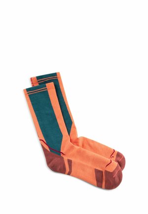 Par de calcetines naranjas de tipo crew con paneles verdes y puntas y talones marrones, colocados planos sobre un fondo blanco.