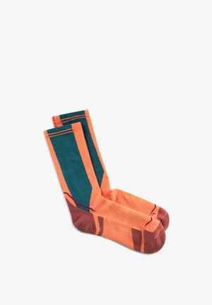 Par de calcetines naranjas de tipo crew con paneles verdes y puntas y talones marrones, colocados planos sobre un fondo blanco.