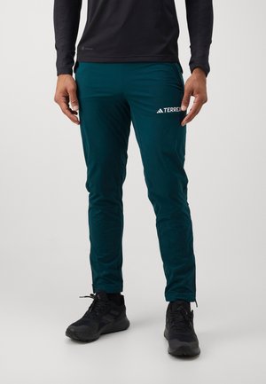 Tirkizne vanjske hlače izrađene od lagane tkanine, s elegantnim dizajnom, elastičnim pojasom i Adidas Terrex logotipom na butu.
