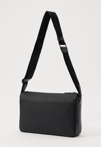 Borsa a tracolla nera realizzata in materiale testurizzato, con chiusura a zip, forma piatta e tracolla regolabile con dettagli in logo impresso.