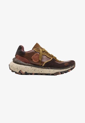 Zapatilla marrón y beige con piel texturizada y paneles de ante, cordones amarillos y una suela gruesa moteada con un patrón de dibujo de camuflaje.