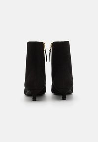 Botine negre din suede, cu toc conic, fermoare la spate și o textură subtilă, având un finisaj neted și un design minimalist.