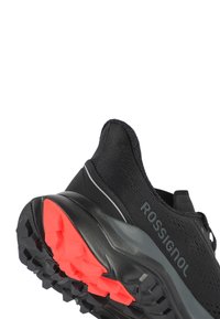Scarpa sportiva nera con tomaia in tessuto, dotata di una suola grigia e un accento arancione brillante sul battistrada. Progettata per trazione e prestazioni.