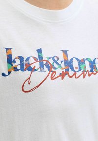 Λευκό μπλουζάκι με πολύχρωμο κείμενο "Jack & Jones" και κόκκινη υπογεγραμμένη λέξη "Denim" τυπωμένη στο στήθος.