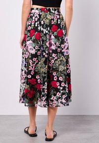 Schwarzer, floral bestickter Rock mit roten, rosa und grünen Mustern; knielang mit elastischem Bund; leichtes, transparentes Material.
