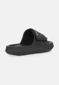 Black slide sandal with a textured rubber sole, open back, and a padded strap featuring a Velcro closure for adjustable fit.