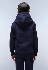 Sudadera azul marino hecha de algodón, con una capucha grande y relajada, puños y dobladillo acanalados, de textura suave y sin patrones visibles.