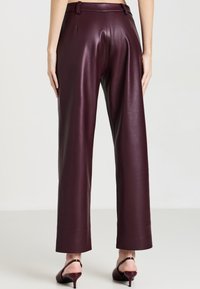 Bordeauxfarbene Kunstlederhose mit geradem Bein, ausgestattet mit einer glatten Textur, maßgeschneideter Taille und umgenähten Säumen.