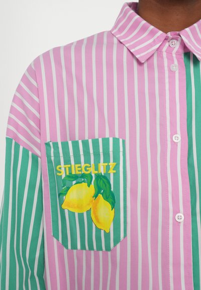 Multifarvet skjorte med lodrette lyserøde og grønne striber. Har en lomme med gule citroner og "STIEGLITZ" broderet i gult. Knap-ophængt design.